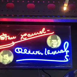 Neonreclame met rode en blauwe letters en twee portretten in gele cirkels