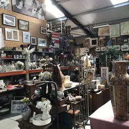 Winkelvloer van kringloopwinkel met meubels, kunstwerken, vazen en decoratieartikelen aan alle kanten