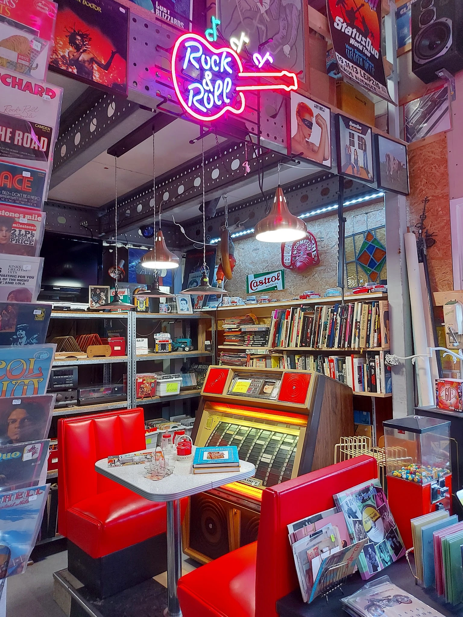 Winkelinterieur met boekenrekken, vintage items, rode stoelen en hangende lampen