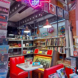 Winkelinterieur met boekenrekken, vintage items, rode stoelen en hangende lampen