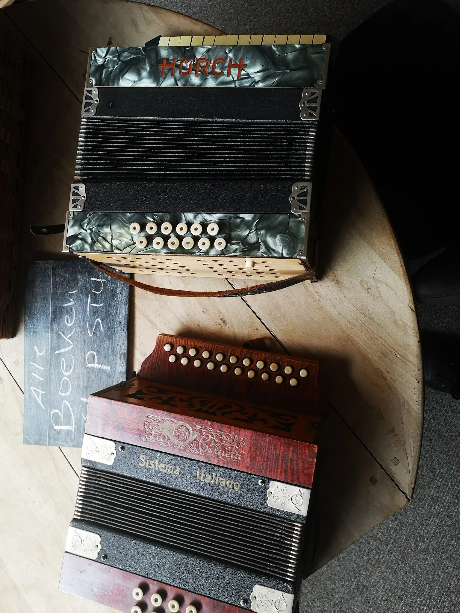 Close-up van twee accordeons met toetsen, één zwart en één bruin, op houten ondergrond