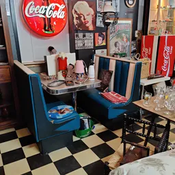 Vintage retro inrichtingsstijl met blauwe stoelen, een ronde tafel, Coca-Cola neonbord en nostalgische decoratie