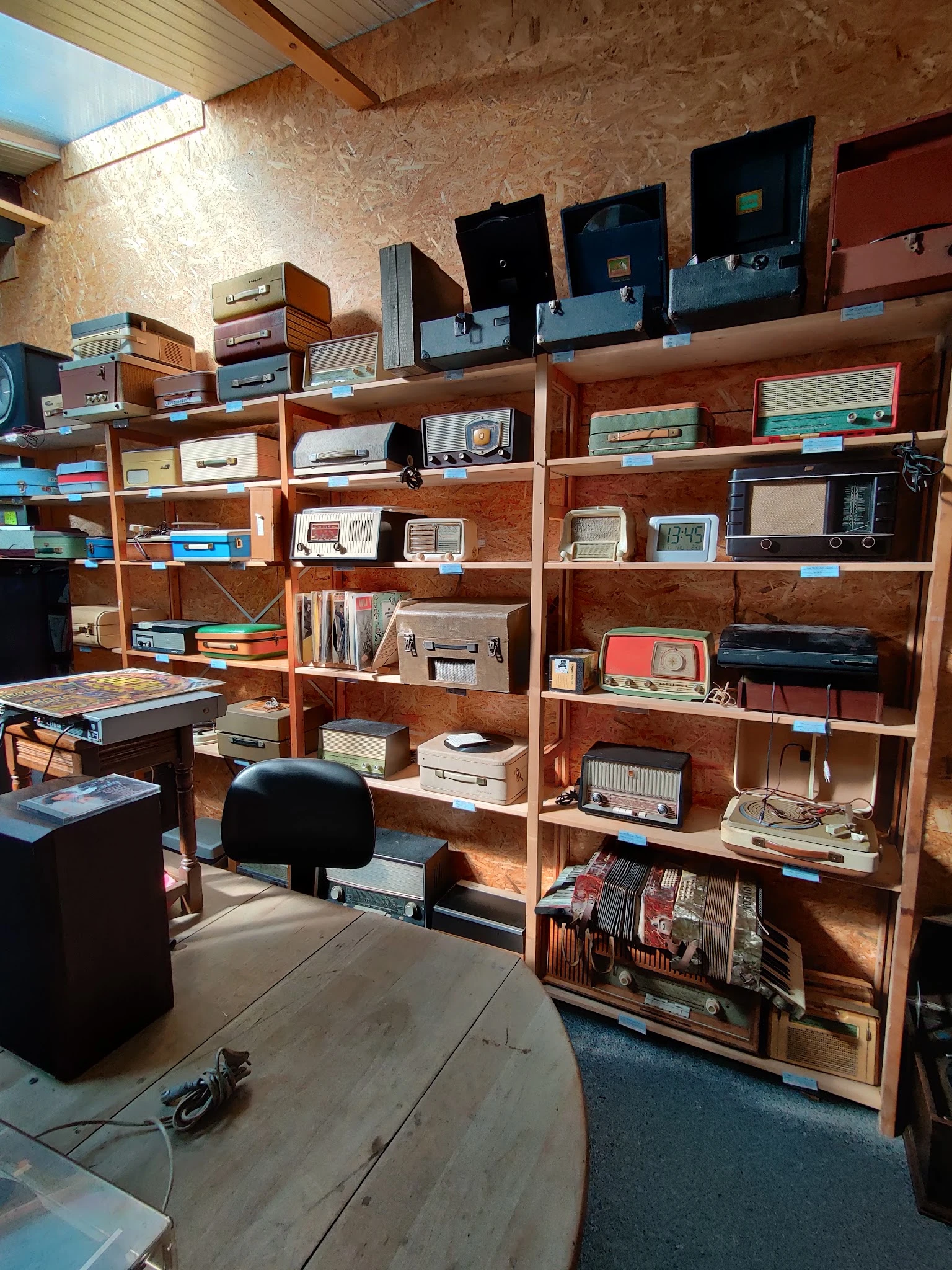 Houten kasten en stellingen vol met vintage elektronica, radios en huishoudapparatuur in een kringloopwinkel