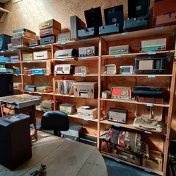 Houten kasten en stellingen vol met vintage elektronica, radios en huishoudapparatuur in een kringloopwinkel