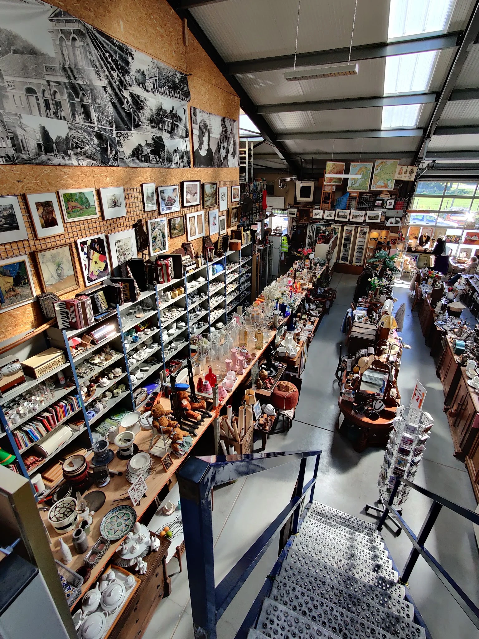 Overzicht van de winkelvloer met stellingen vol kunstwerken, boeken, servies en diverse tweedehandsartikelen