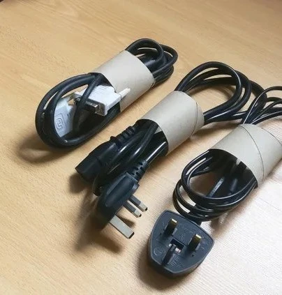 Drie elektrische snoeren met stekkers en witte labels, op houten ondergrond