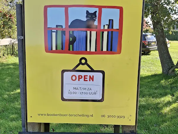 Gele gevel van kringloopwinkel met rood raamkader met boeken, open-bord en website-informatie