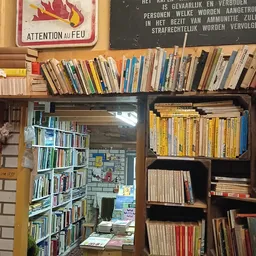 Boekenkasten en stellingen vol met tweedehands boeken in verschillende kleuren en formaten in een kringloopwinkel