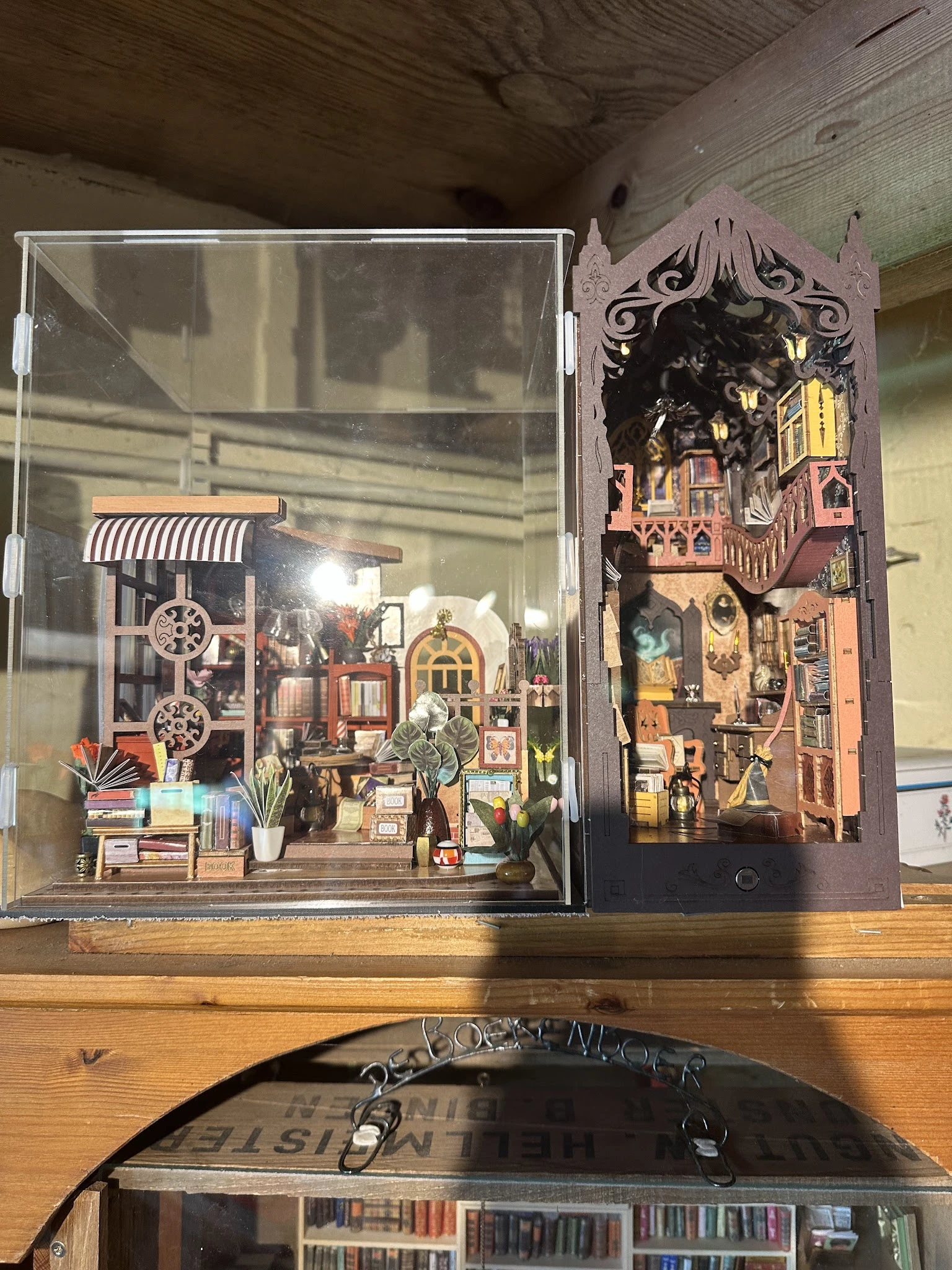 Twee miniatuurbouwsets in glazen vitrines met gedetailleerde huisjes en straatscènes