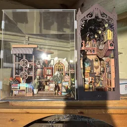 Twee miniatuurbouwsets in glazen vitrines met gedetailleerde huisjes en straatscènes