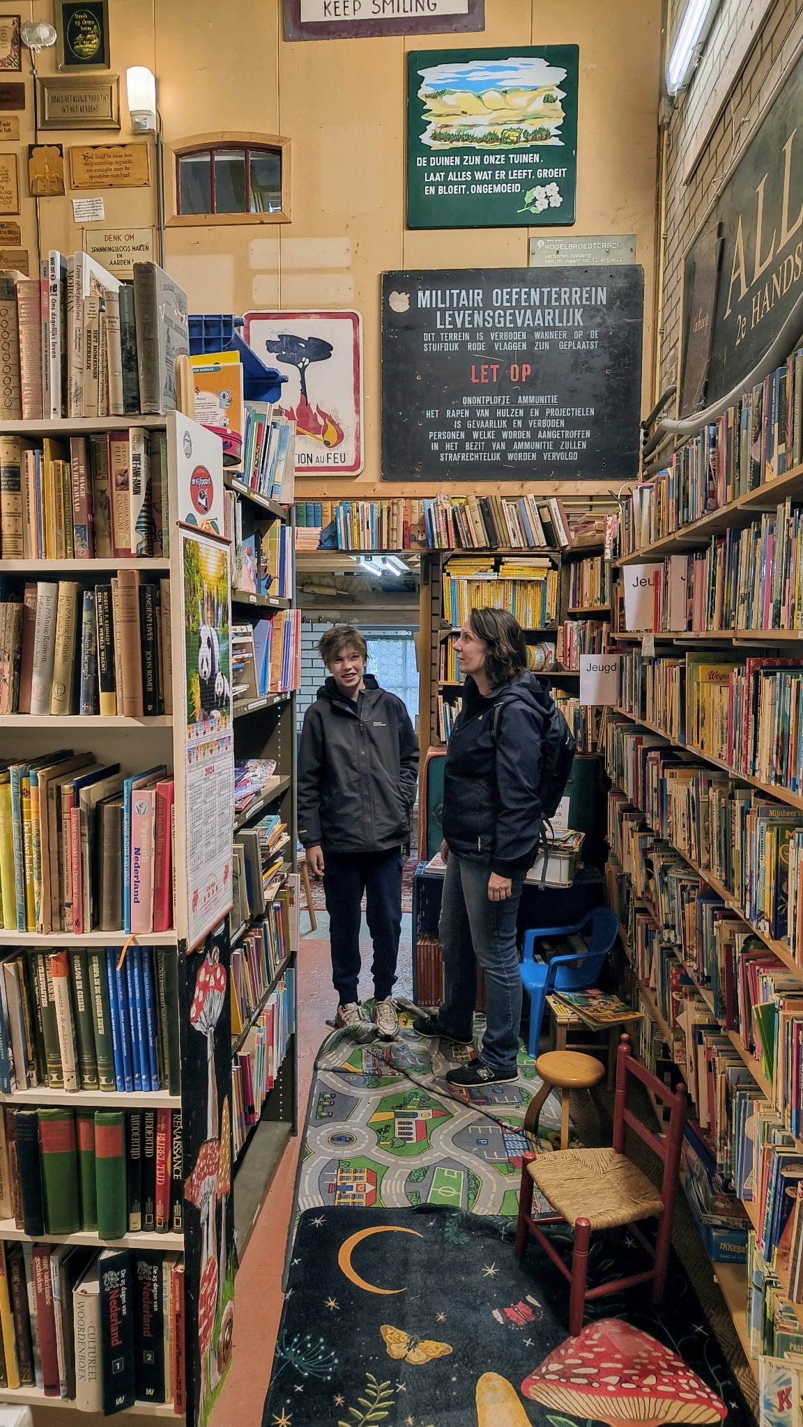 Twee personen in een boekenwinkel tussen hoge stellingen met boeken