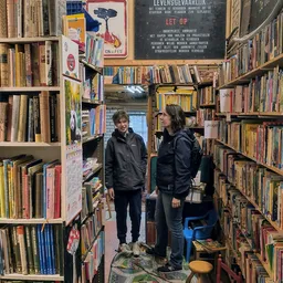 Twee personen in een boekenwinkel tussen hoge stellingen met boeken