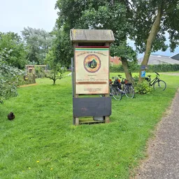 Informatiebord voor fietsers naast een pad met fietsen op de achtergrond