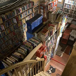 Overzicht van boekenwinkel met volle stellingen en dozen met boeken op meerdere niveaus
