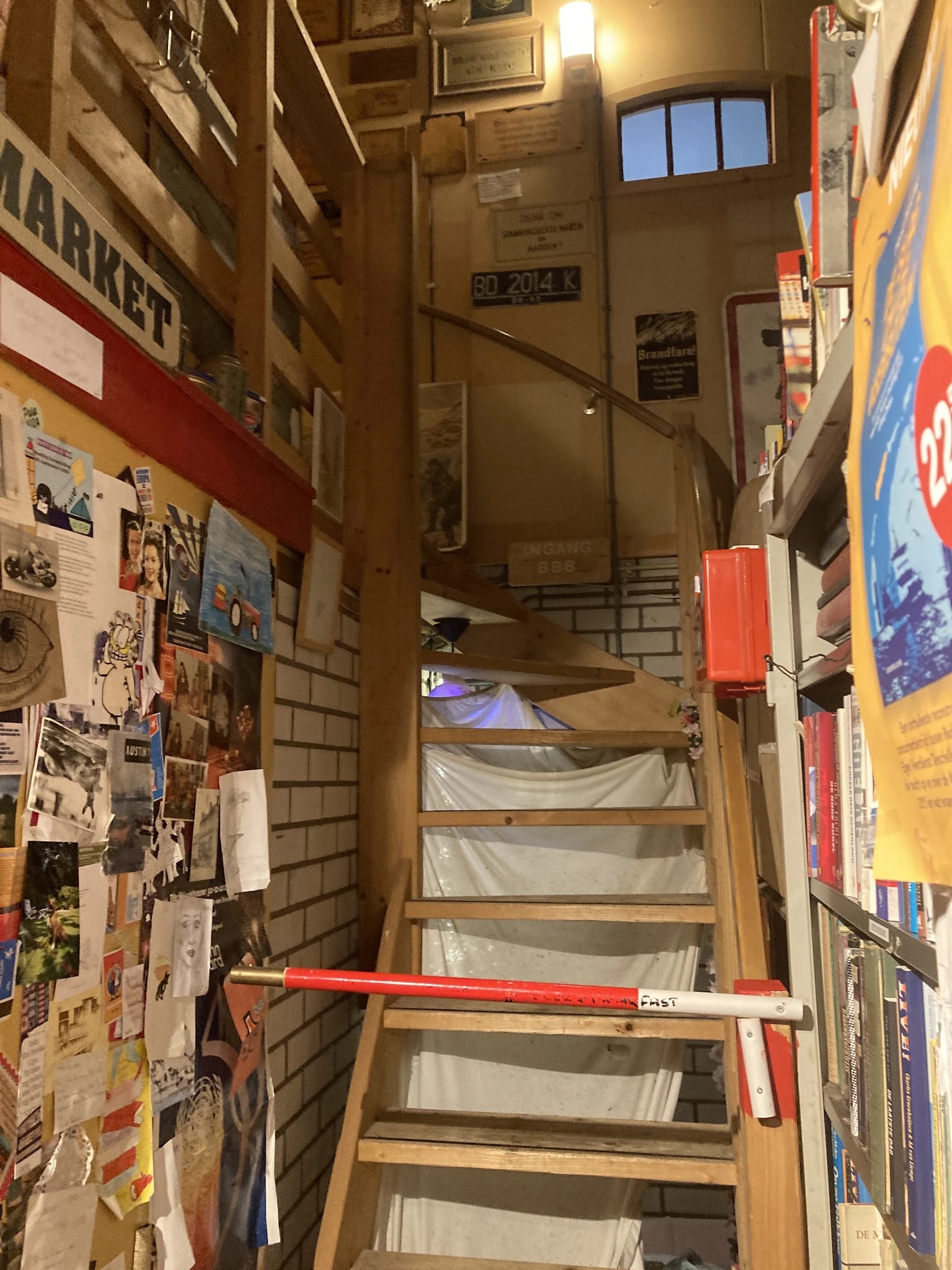 Trappenhuisgebied met versiering en posters aan muren, zicht op bovenverdieping