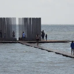Mensen waden in zeewater bij een houten constructie