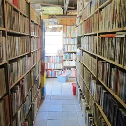 Smalle gang tussen twee hoge houten boekenrekken in een tweedehands boekhandel