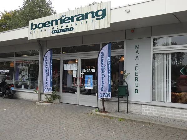 Gevel van Boem kringloopwinkel met uithangteken, etalageramen en open deuren