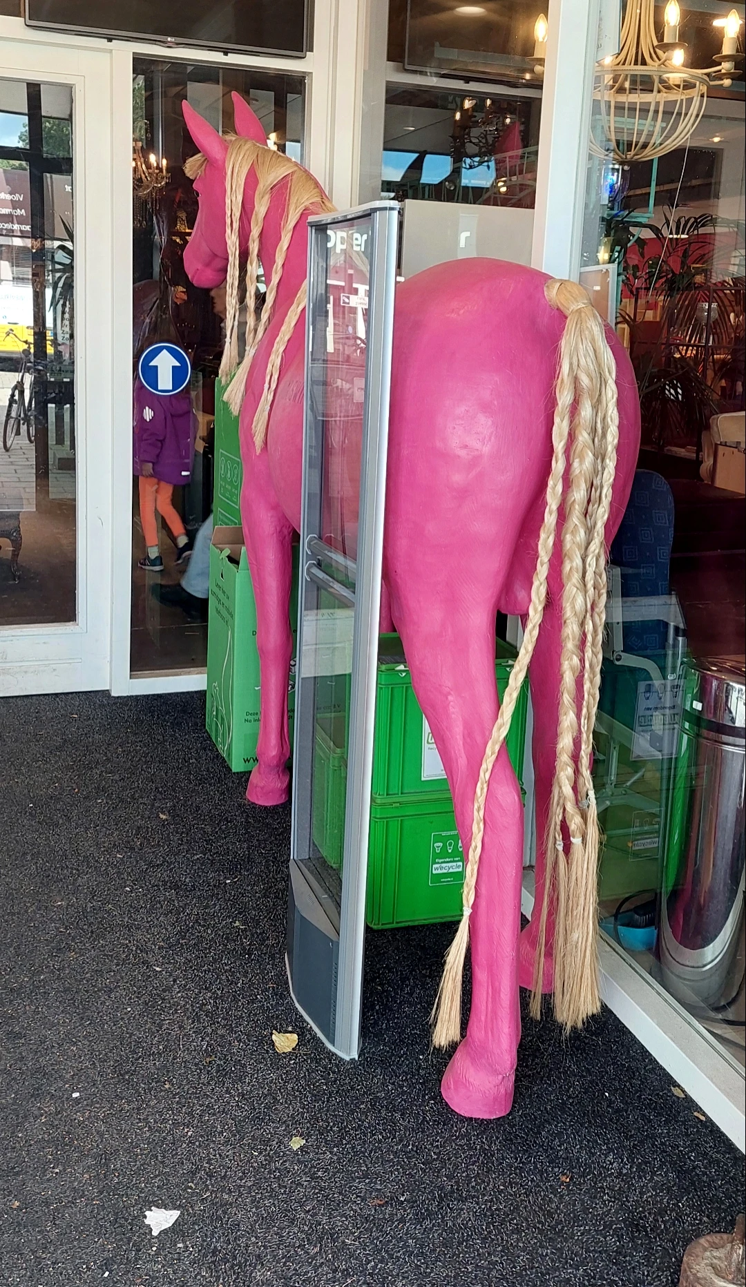 Uitgestalde tweedehands kleding op hangers en rekken in de winkel, waaronder roze en groene kledingstukken