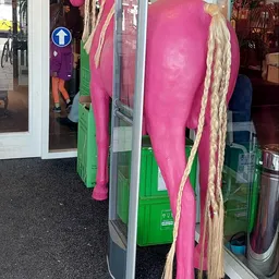 Uitgestalde tweedehands kleding op hangers en rekken in de winkel, waaronder roze en groene kledingstukken
