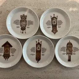 Vijf decoratieve borden met afbeeldingen van vintage koekoeksklokken en beschrijvende teksten