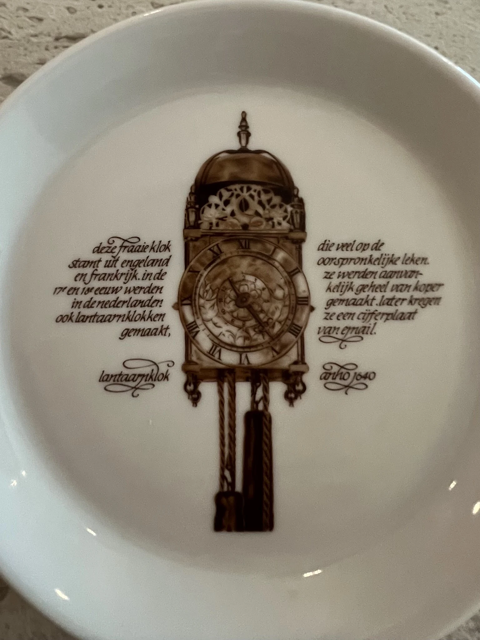 Decoratief bord met afbeelding van een antieke staartklok en Nederlandse tekst