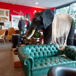 Winkelvloer met turquoise chesterfield-bank, groot olifantbeeld en diverse meubels en decoraties