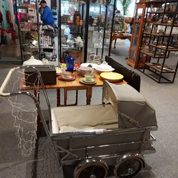 Uitgestalde serviesgoed, een kinderwagen en diverse huishoudelijke artikelen in de winkel