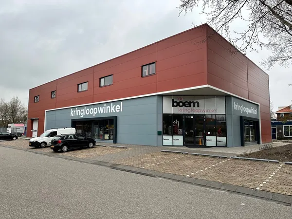 Gevel van Boem Kringloopwinkel met rode bakstenen bovenbouw en blauwe winkelfront met glazen deuren