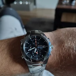 Close-up van een Seiko chronograaf horloge met zwarte wijzerplaat aan de pols van een persoon