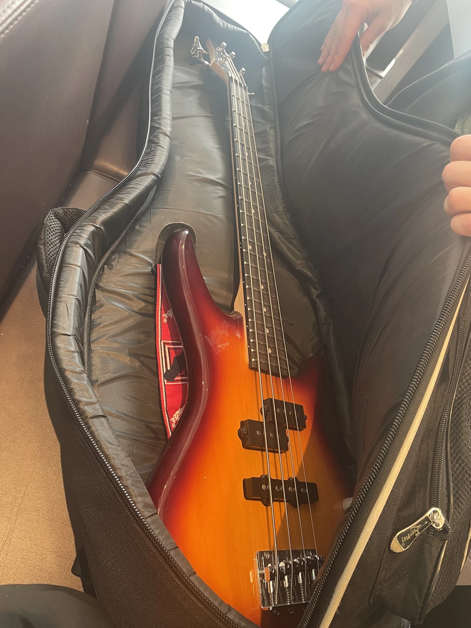Close-up van een roodoranje elektrische basgitaar in een zwarte gigbag