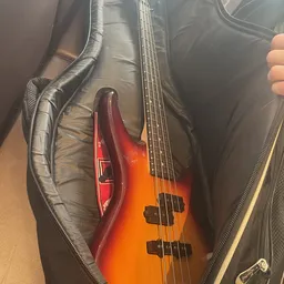 Close-up van een roodoranje elektrische basgitaar in een zwarte gigbag