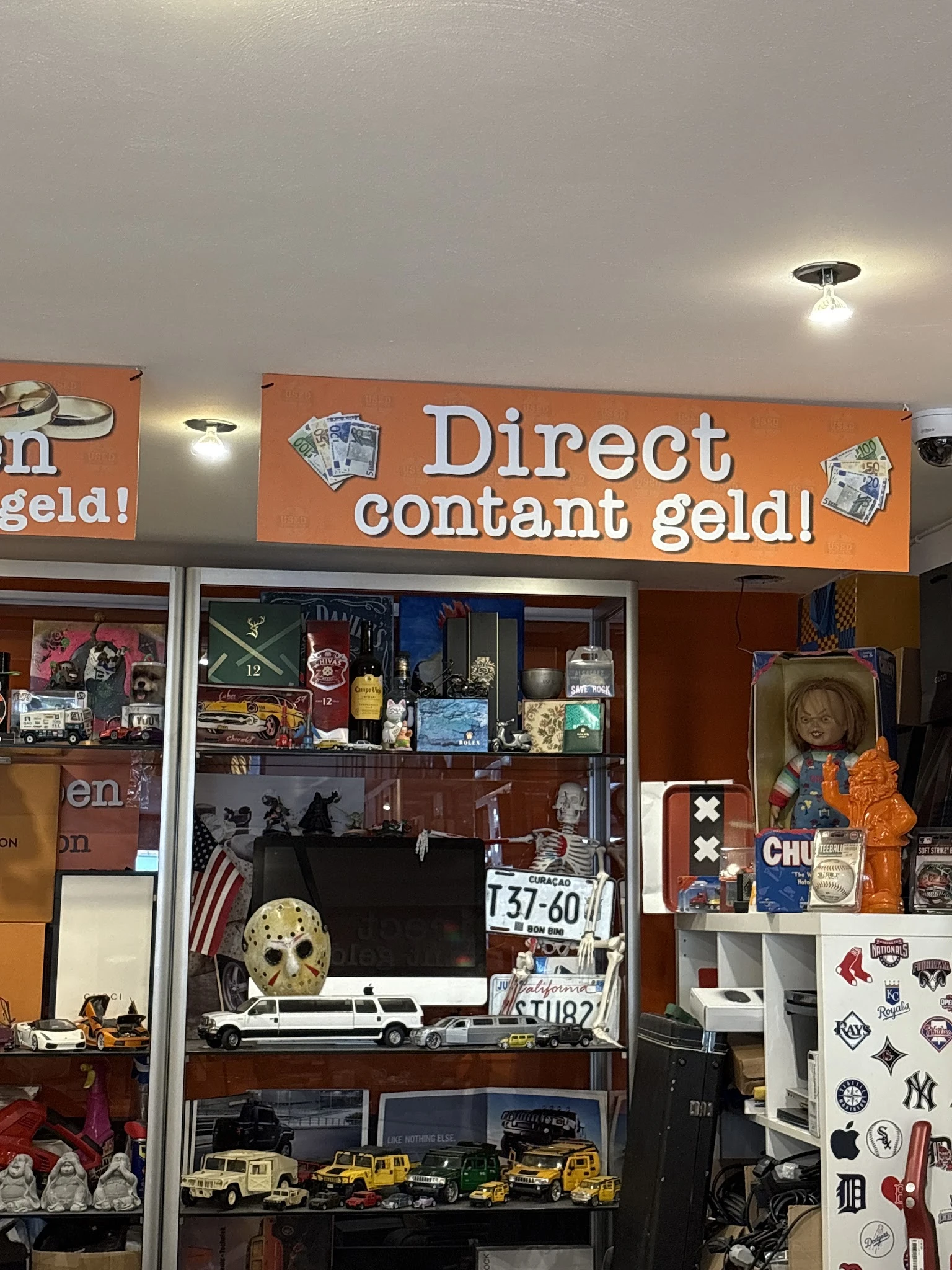 Winkeletalage met oranje koppeluiting en uitgestalde tweedehandsartikelen achter glas