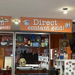 Winkeletalage met oranje koppeluiting en uitgestalde tweedehandsartikelen achter glas