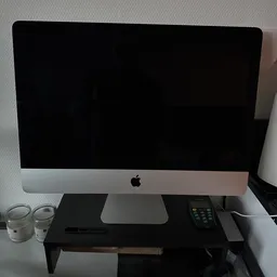 Apple iMac-computermonitor op een bureau met twee waterglazen ernaast