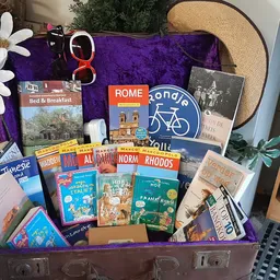 Vintage koffer volgestouwd met reisgidsen, kaarten en reisboeken over verschillende Europese bestemmingen