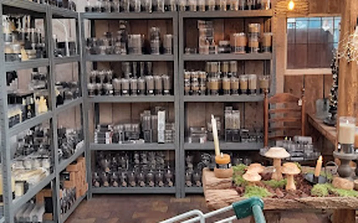 Winkelinterieur met grijze stellingen vol flessen en potten, houten tafel met decoratieve items op de voorgrond