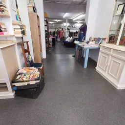 Winkelvloer van kringloopwinkel met stellingen, kleding aan hangers, boeken en diverse spullen uitgestald