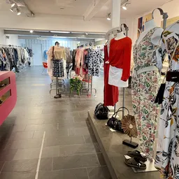 Winkelvloer van kledingwinkel met rekken, kledinghangers en vitrines met tweedehands designerkleding