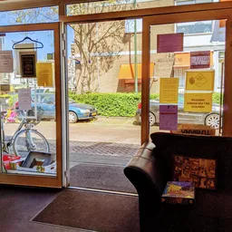 Binnenaanzicht kringloopwinkel met uitgestalde artikelen, fiets bij raam, zicht op straat buiten