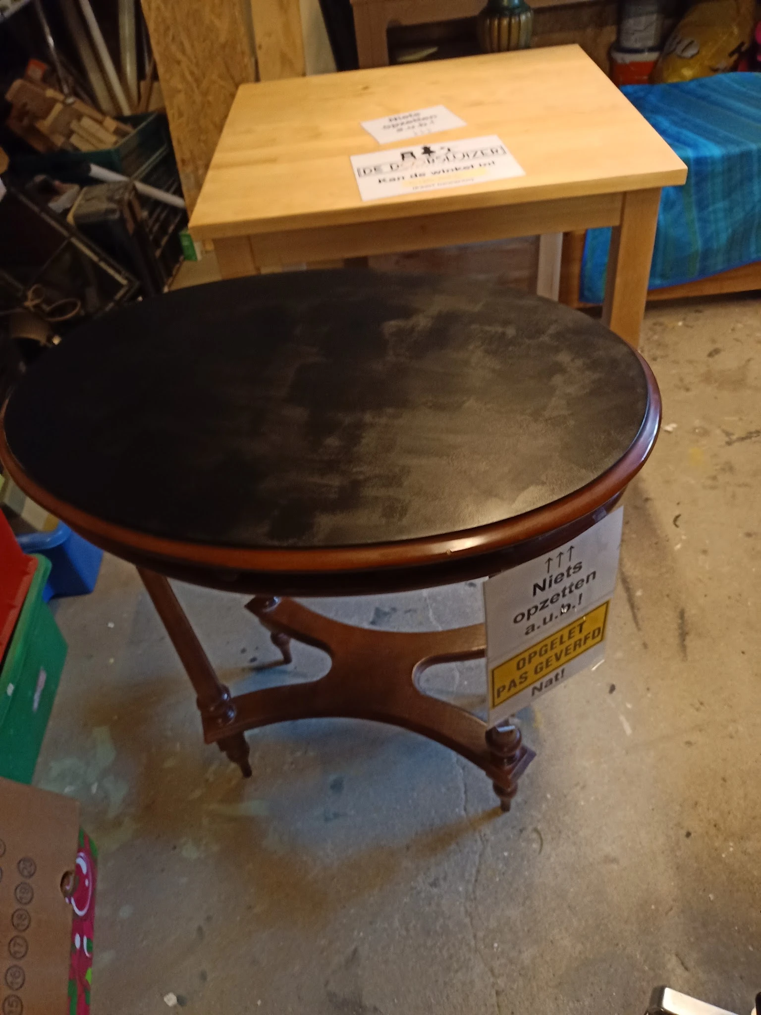 Ronde houten salontafel met zwart blad en prijskaartje eraan