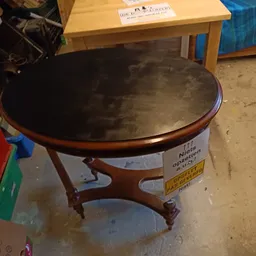 Ronde houten salontafel met zwart blad en prijskaartje eraan