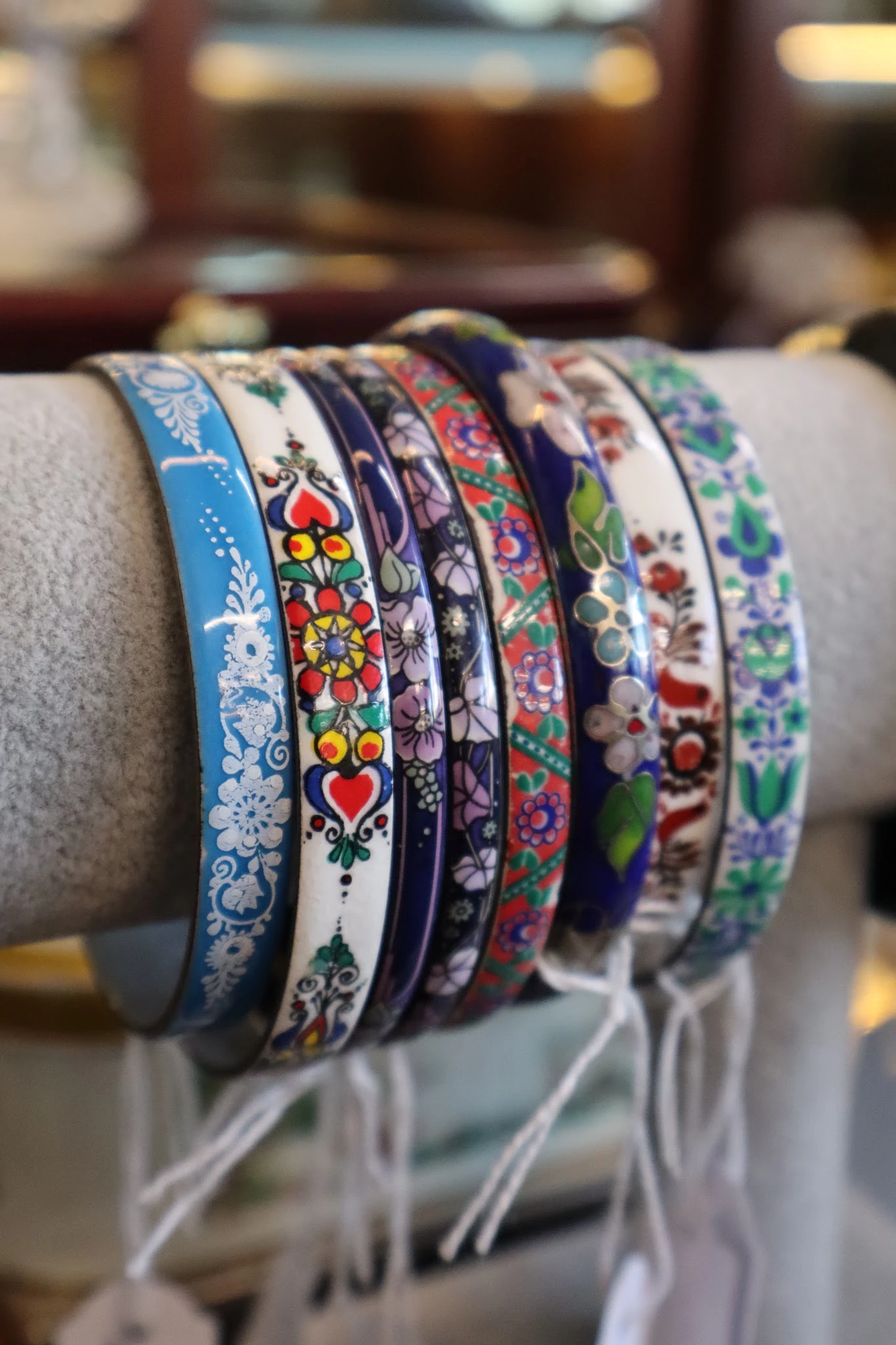Zes decoratieve armbanden met verschillende gekleurde etnische en bloemmotieven op een grijze ondergrond