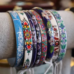 Zes decoratieve armbanden met verschillende gekleurde etnische en bloemmotieven op een grijze ondergrond