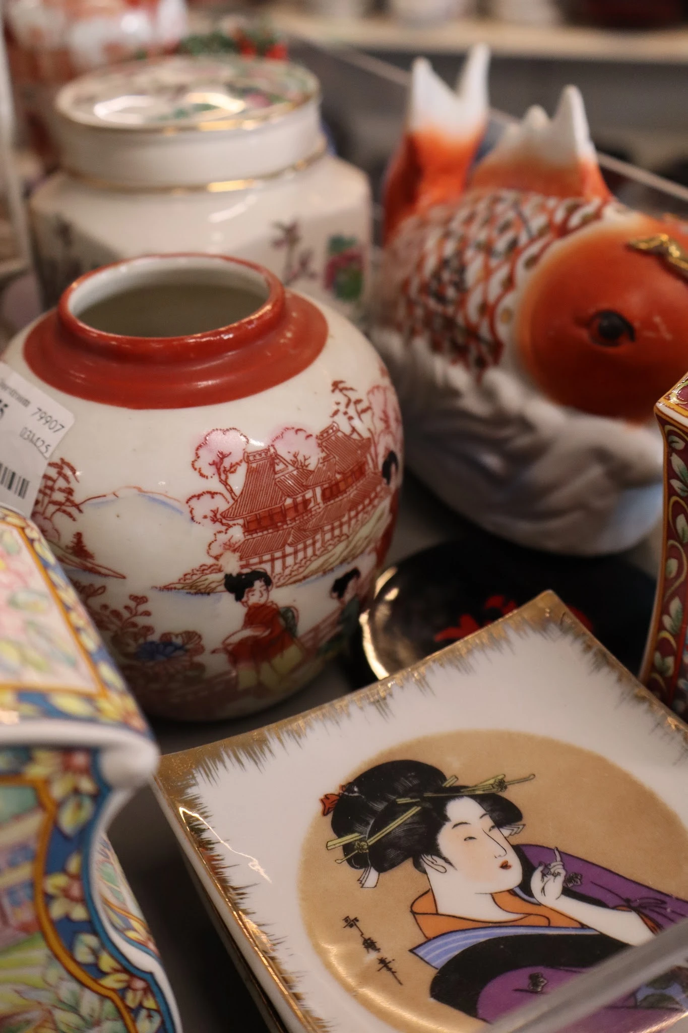 Close-up van een rood-wit porseleinenen pot met oosters decor en andere decoratieve items op achtergrond