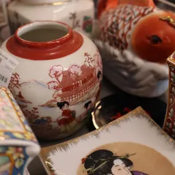 Close-up van een rood-wit porseleinenen pot met oosters decor en andere decoratieve items op achtergrond