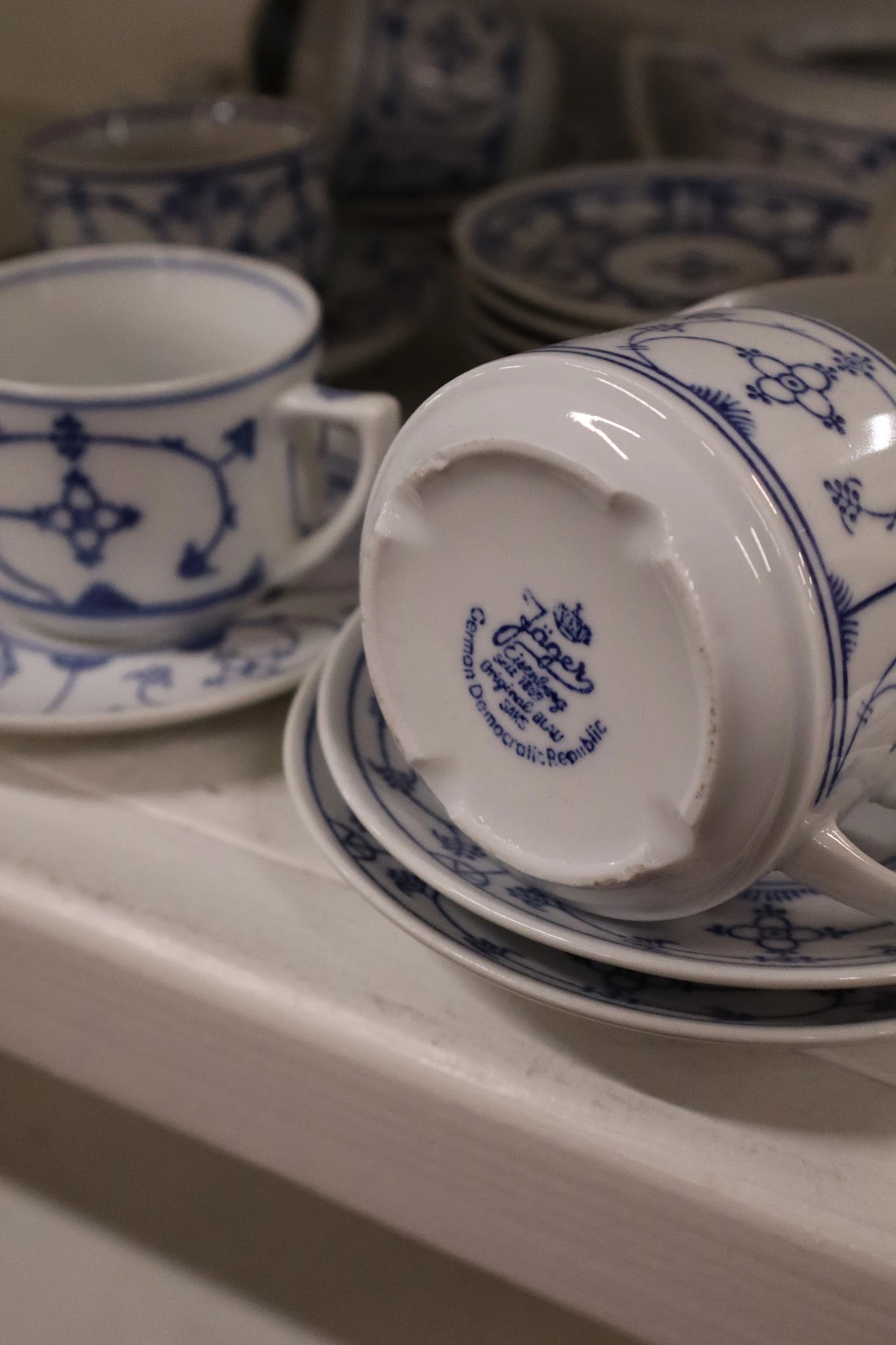 Close-up van een wit porseleinen kopje met blauw decoratief patroon en fabrikantsmerk op de bodem