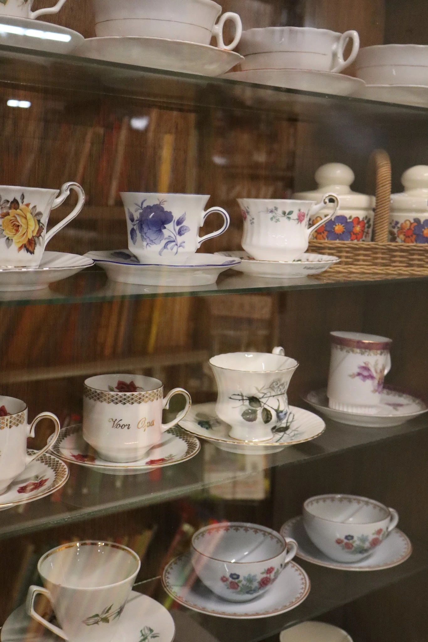 Vitrinekast met antiek porselein servies, kopjes met bloemmotieven en gouden accenten