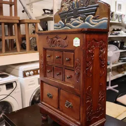 Houten kastje met gesneden decoratie en meerdere kleine laden met koperen handgrepen