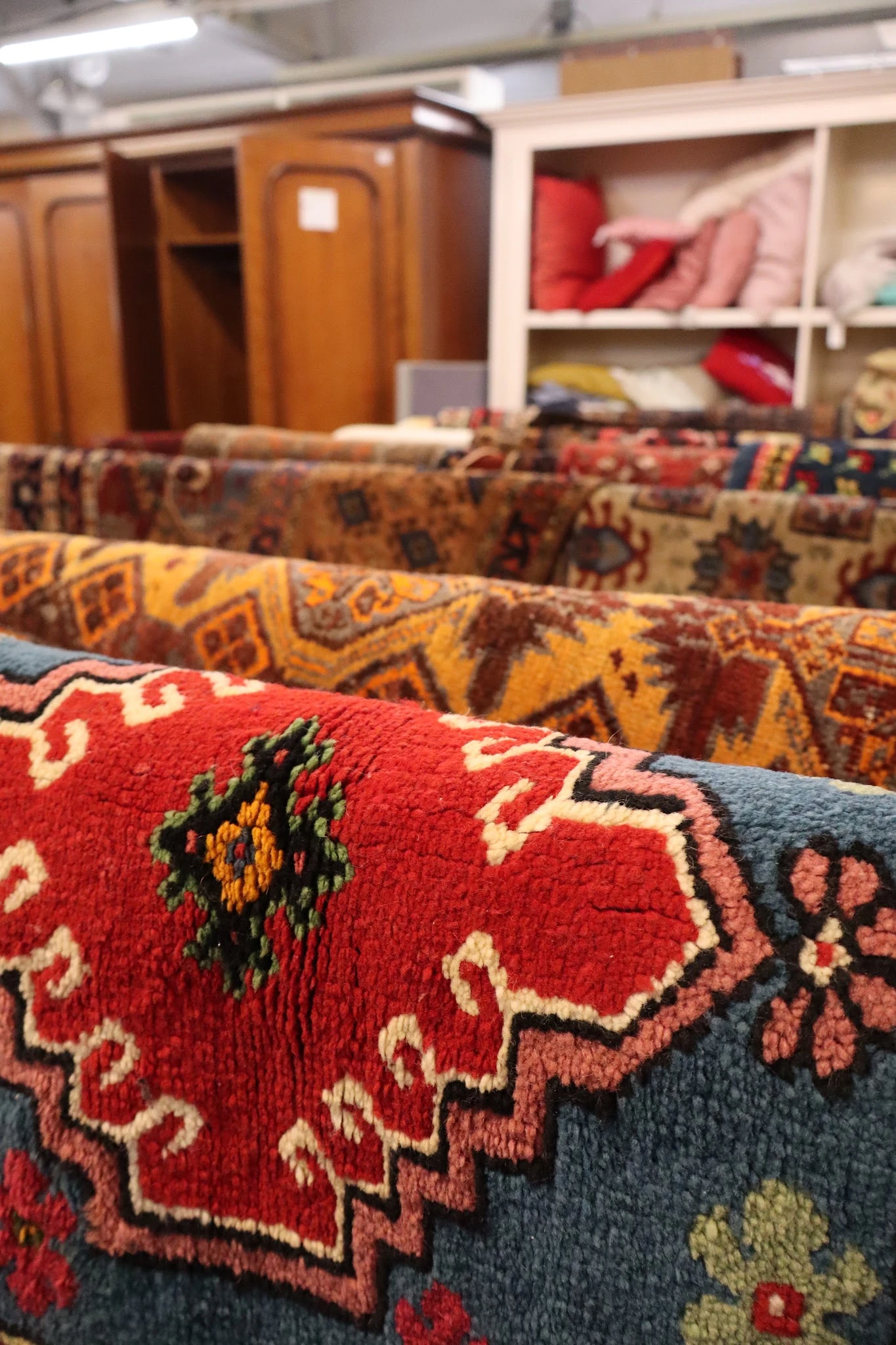Stapel traditionele handgeknoopte tapijten met diverse kleurige patronen in rood, geel en blauw